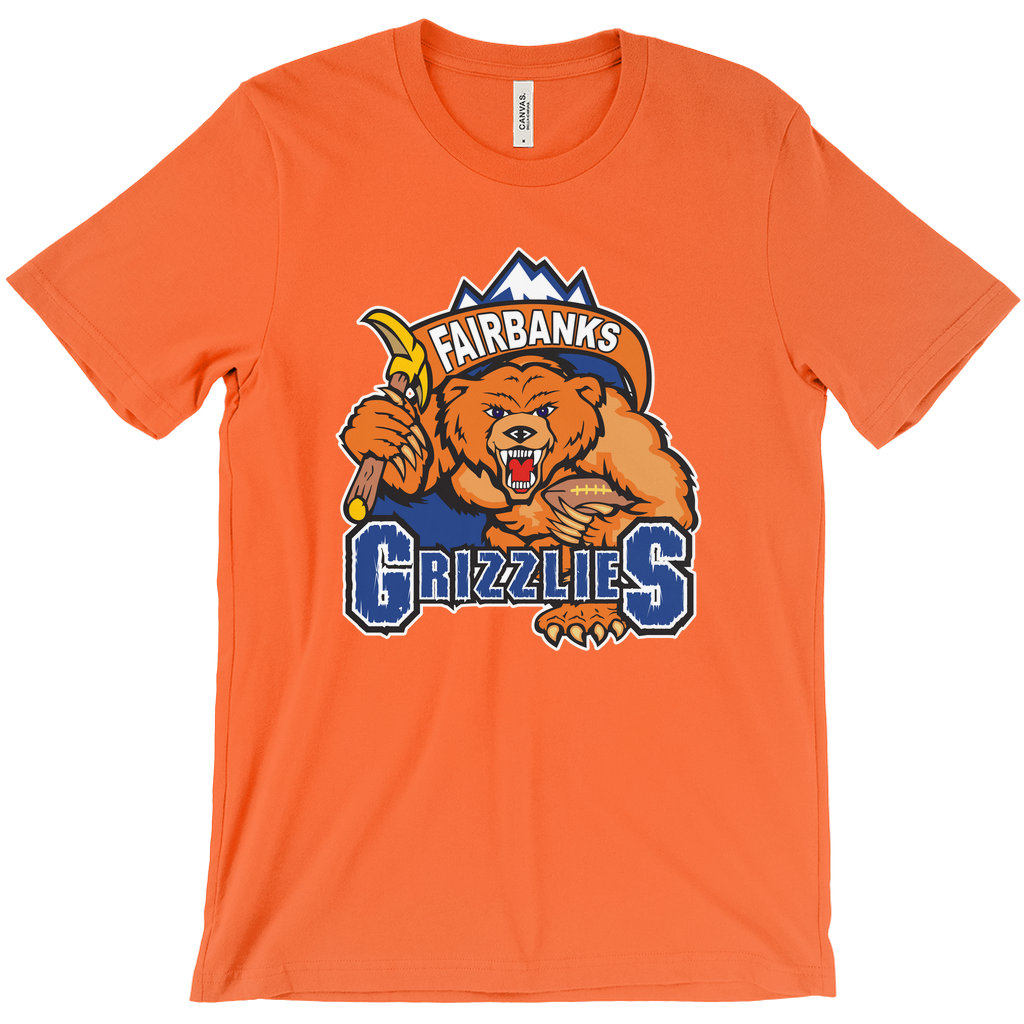 Fairbanks Grizzlies T-shirt. Orange. Mountain peaks with brown banner with Fairbanks in white inside. Below, a growling bear, face on, holding a pick in his right arm and a football in his left over GRIZZLIES on blue with white trim. Royal Retros