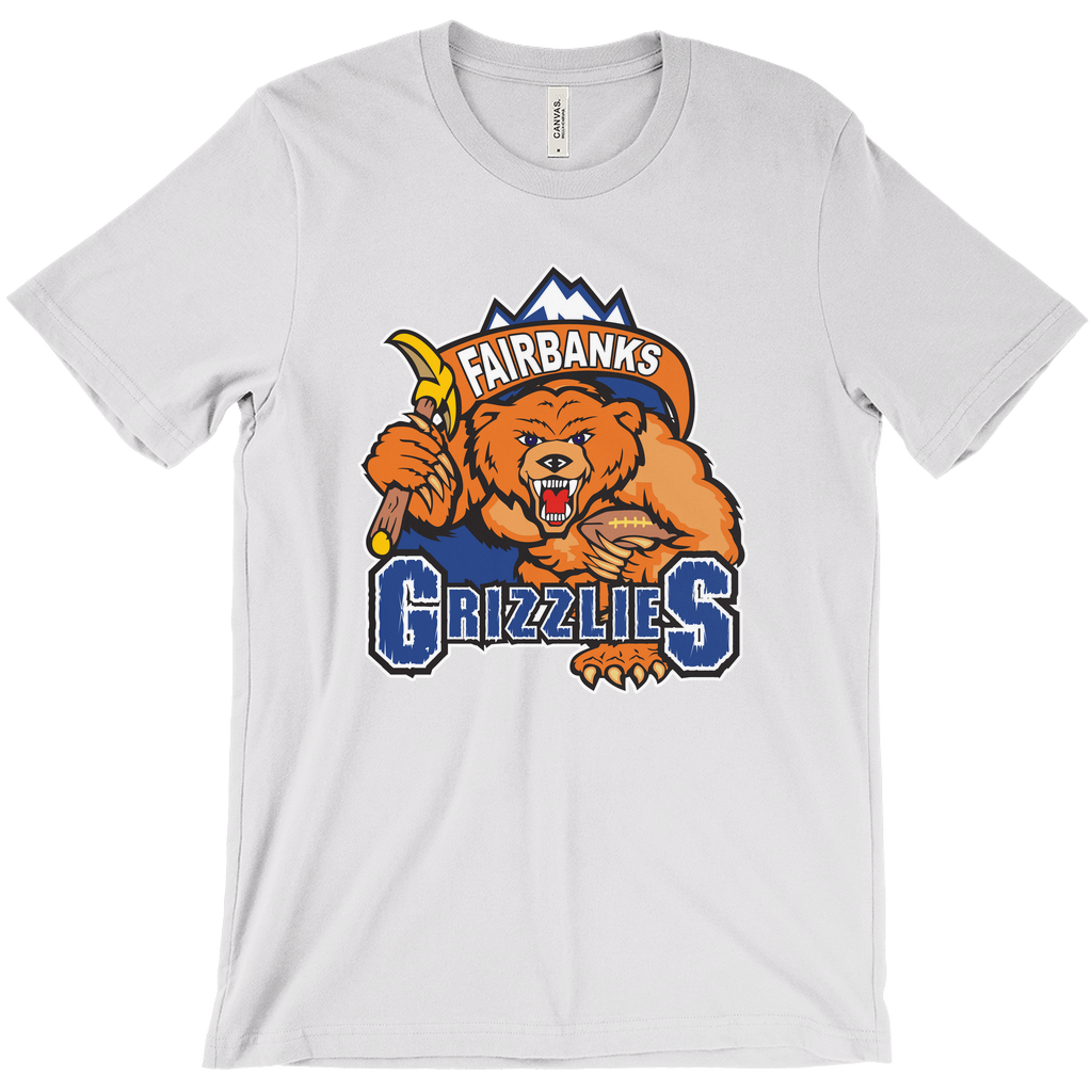 Fairbanks Grizzlies T-shirt. White. Mountain peaks with brown banner with Fairbanks in white inside. Below, a growling bear, face on, holding a pick in his right arm and a football in his left over GRIZZLIES on blue with white trim. Royal Retros