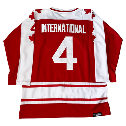 1974 Team Canada hockey jersey. Red. White and red color. Half red, half white sleeves. Red maple leaves down white side with #44 red above last one. Red and white bands above waist. #4 in white large on back with International in white above.  Royal Retros