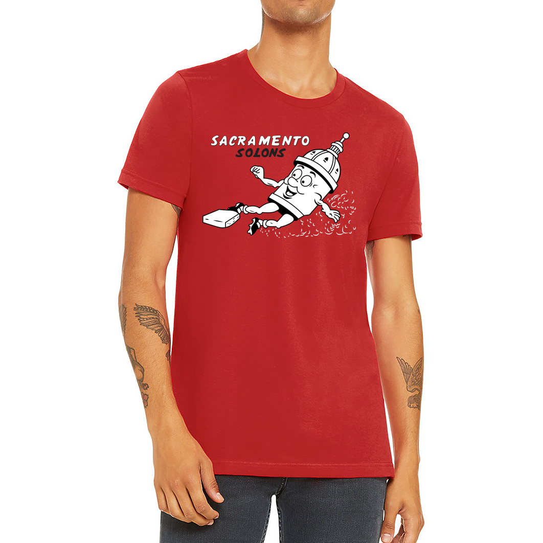 Sacramento Solons T-shirt. Red. Sacramento in white, Solons in black below on right chest. Image of cartoon capital building sliding into a base, right to left. Royal Retros