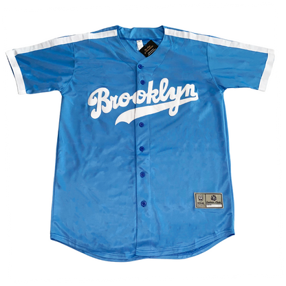 Brooklyn Dodgers light blue button-up baseball jersey. White bands on shoulders and around sleeve ends. Brooklyn in cursive in white with text tail. Royal Retros