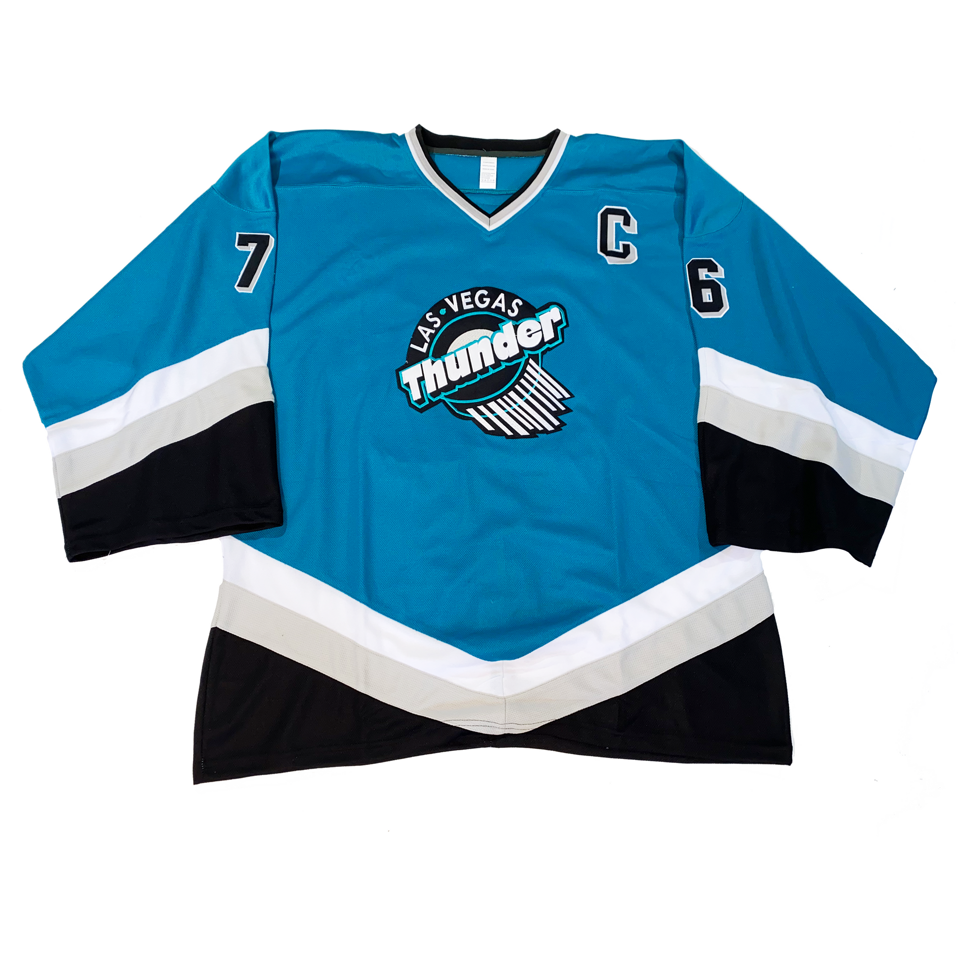 Las Vegas Thunder hockey jersey teal. Black and white diagonal bands on sleeves and waist. Logo on chest. Las Vegas in white over Thunder in white diagonally over hockey puck with swish marks leading away from the bottom right down. Royal Retros