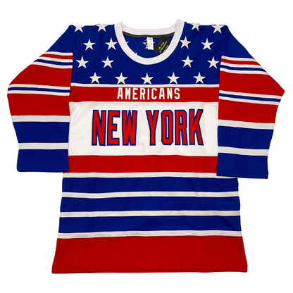 New York Americans hockey jersey. White collar. Blue shoulders with white stars, Alternating red, white, and blue bands of various sizes on sleeves and on bottom half of jersey. Americans in white on red band across chest. Large white band below with New York in red with blue trim. Royal Retros